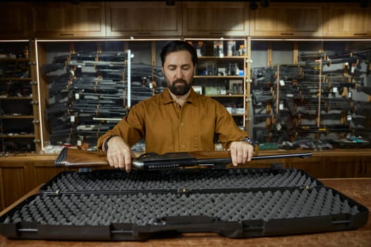 Salesman packing gun machine in case for safety storage. Weapon store with military equipment for army