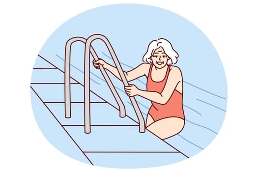 Elderly woman in pool of hotel or spa after finishing aqua treatments for healthy lifestyle. Retired woman in swimming suit in pool leaves water completing workout and wellness fitness session