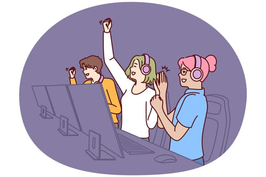 Team of delighted esports players participating in gamer competition in online multiplayer game or MMORPG. Teenage boys and girls sit at table with computers and celebrate victory in tournament