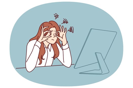 Sleepy businesswoman trying to stay awake sitting at workplace with monitor is feeling tired due to overwork. Businesswoman doing office work suffering from vision problems and strict deadlines
