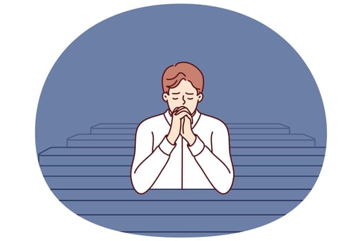 Christian man sits and prays in catholic church, turning to god to confess or ask for help. Believing guy in church and prays to feel psychological relief or observe religious ritual