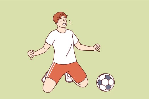 Man football player scores goal against opponent during tournament and takes winning stance on knees. Guy celebrates winning over rival team in football at international championship