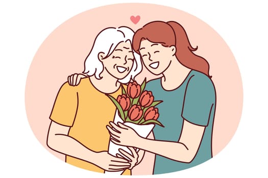 Woman hugs elderly mother and gives bouquet of flowers congratulating with birthday or mother day and thanks for good upbringing. Grown up daughter takes care of mother of retirement age