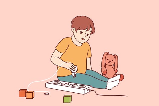 Little boy plays with electrical appliances at risk of getting electric shock due to lack of attention from parents. Child spends time alone playing with electrical outlet that can cause injury