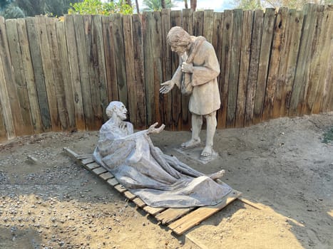 Indio, California, USA– March 4, 2022:  Statue in a park of the good Samaritan or Jesus healing a man.