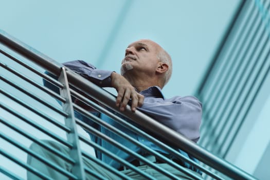 Mature executive in a modern urban setting is deep in thought, possibly pondering the challenges and opportunities that lie ahead