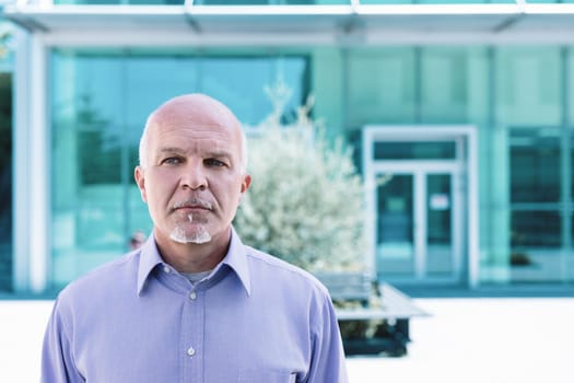 Mature businessman exudes confidence and wisdom outside a modern office building, embodying determination and ambition in his career