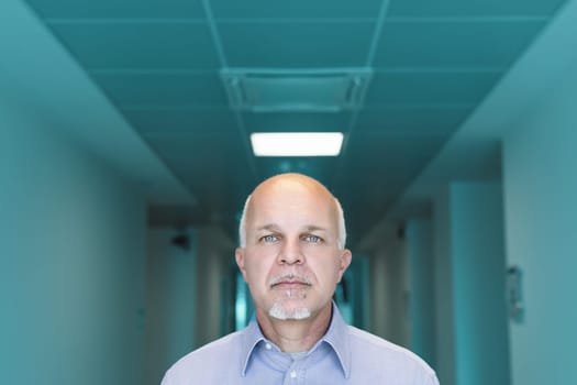 Doctor is standing in a sterile looking hospital corridor with a serious expression, highlighting the important responsibility of medical professionals