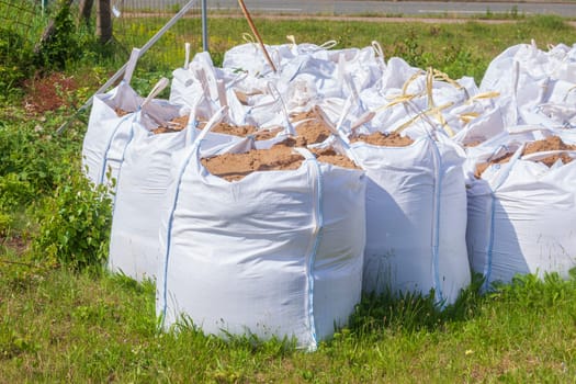 White garbage bags with construction waste standing on a meadow, Germany