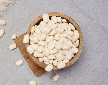 Raw white beans in a plate on the table, top view