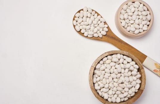 Raw white beans in a plate on the table, top view. Copy space
