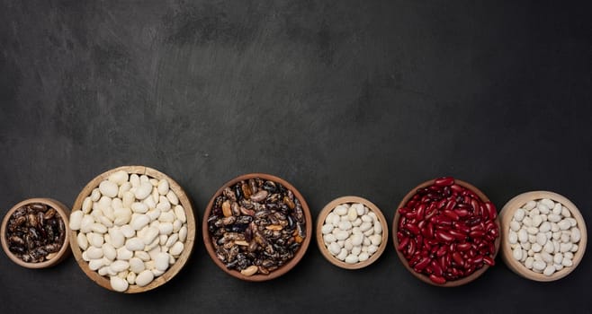 Raw white and red beans in a plate on a black table, top view. Assortment. Copy space
