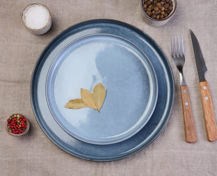 Empty round ceramic plate on the table with spices, top view