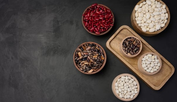 Raw white and red beans in a plate on a black table, top view. Assortment. Copy space