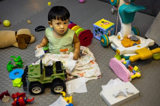 Adorable toddlers playing among the many toys at home. A mess in the children's room.