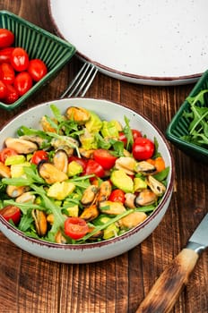 Salad of mussels, arugula, tomato and avocado. Seafood salad.
