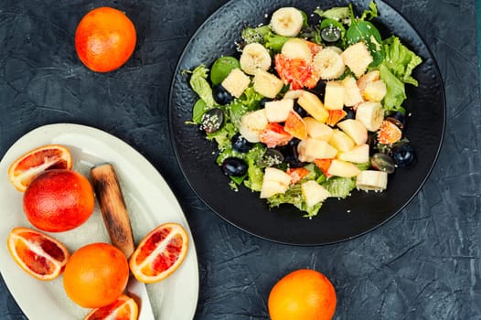 Juicy salad of fresh red orange, apple, banana and lettuce. Healthy eating.