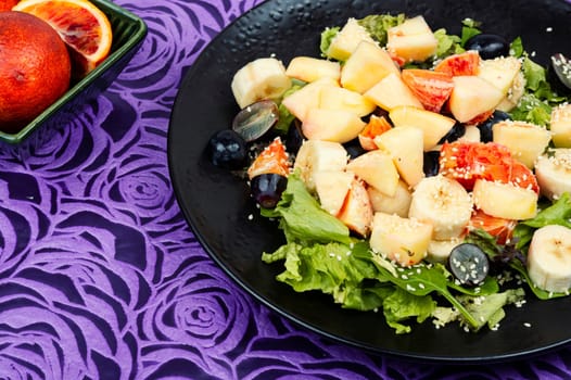 Juicy salad of fresh red orange, apple, banana and lettuce. Healthy eating.