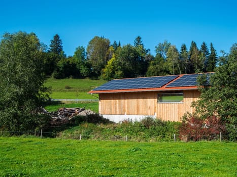 View of a barn roof covered with photovoltaic panels in Bavaria in summer.