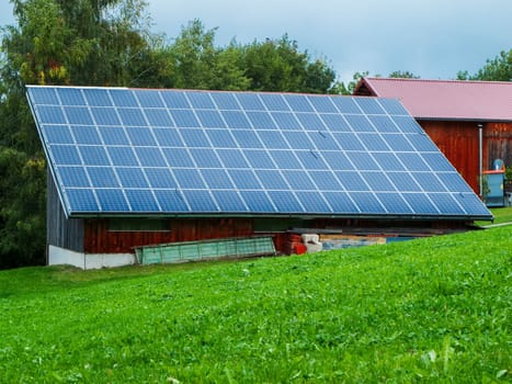 View of a barn roof covered with photovoltaic panels in Bavaria in summer.