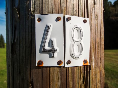 Close-up of a wooden electricity pole with nailed numbers 4 and 8 made of stamped sheet metal.