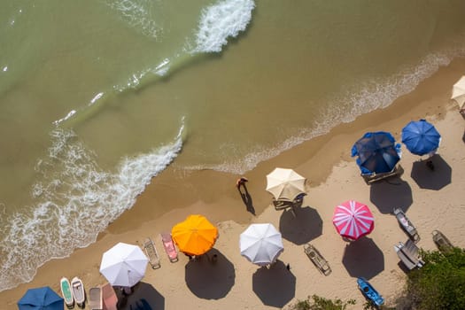 Aerial view of people on the beach, with colorful blankets and umbrellas.