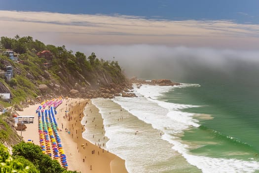 Aerial view of people on the beach, with colorful blankets and umbrellas.