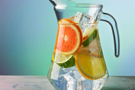 Close-up of a refreshing fruit-infused water pitcher with ice cubes and slices of citrus fruits.