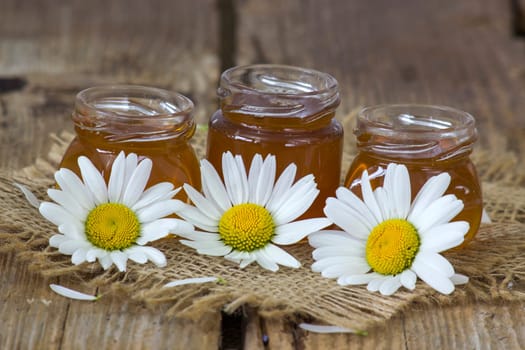 honey and daisies flowers on old wooden background