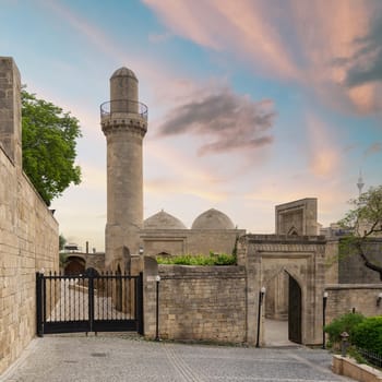 The Shah Mosque minaret rises above the surrounding buildings in Baku, Azerbaijan. Attached to the Palace of the Shirvanshahs, before sunset this mosque is a prominent landmark in the city
