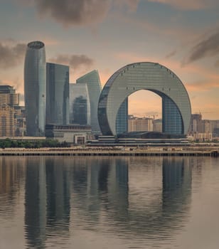 The Crescent Development Project features distinct modern architecture, including the Crescent Hotel, set against a beautiful sunset with reflections on the Caspian Sea in Baku, Azerbaijan