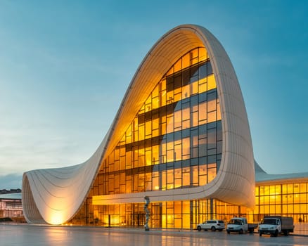 The Heydar Aliyev Centre in Baku, Azerbaijan, glows warmly in the evening with its unique, flowing architecture