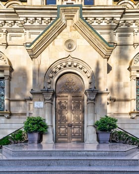 Close-up of Holy Myrrhbearers Cathedral entrance in Baku, Azerbaijan. Metal double doors with intricate designs lead to stone facade