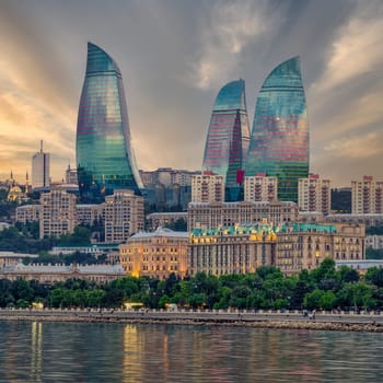 Night view of the iconic illuminated Flame Towers in Baku, Azerbaijan, The modern architecture of the buildings is reflected in the calm waters of the Caspian Sea
