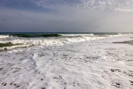 Foamy sea waves on the sandy beach of Bajondillo in Torremolinos, Malaga, Costa del Sol, Spain