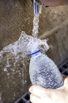 filling a bottle with water at a fountain on the street, thirst