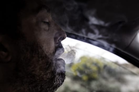 Detail of young person releasing smoke from the mouth, addiction, nicotine