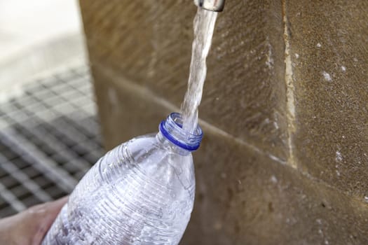 filling a bottle with water at a fountain on the street, thirst
