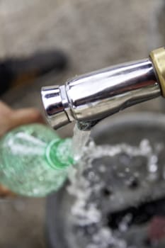 filling a bottle with water at a fountain on the street, thirst