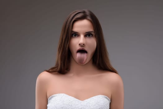 Young woman playfully sticks out her tongue in disgust, showing negative emotions with humor