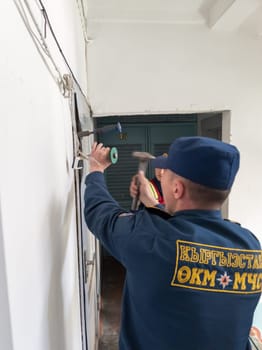 Rescuers from the Ministry of Emergency Situations of Kyrgyzstan break open a metal door to an apartment in an apartment building in Bishkek, Kyrgyzstan April 22, 2023