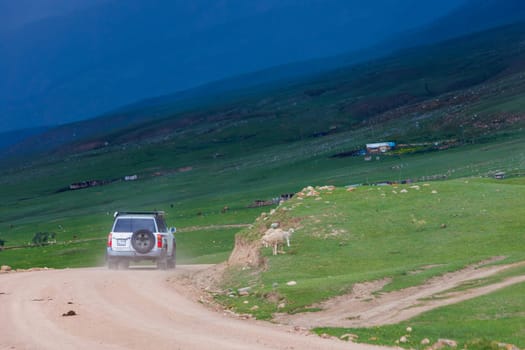 adventurous offroad journey through remote countryside in mountain ravine with dramatic pre-storm cloudy skies in Semenovskoye gorge, Kyrgyzstan at July 5, 2023