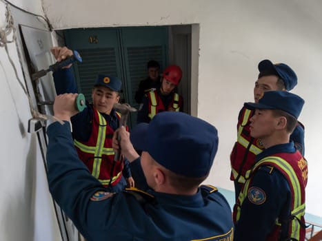 Rescuers from the Ministry of Emergency Situations of Kyrgyzstan break open a metal door to an apartment in an apartment building in Bishkek, Kyrgyzstan April 22, 2023