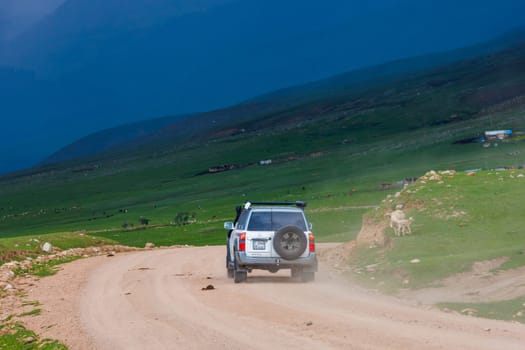 adventurous offroad journey through remote countryside in mountain ravine with dramatic pre-storm cloudy skies in Semenovskoye gorge, Kyrgyzstan at July 5, 2023