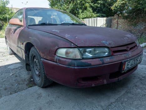 heavily used falling apart neglected car at the sunny summer street of Central Asia in Sokuluk, Kurgyzstan - June 5, 2023