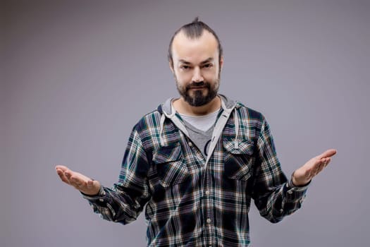 Studio portrait of a bearded man wearing casual clothes, gesturing with open arms while showing indecision, confusion, or perplexity