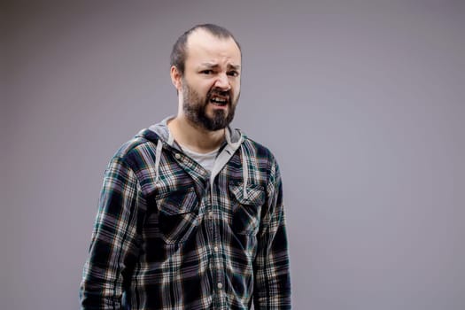 Man with a beard wrinkles his nose and purses his lips in disgust, showing strong feelings of displeasure and revulsion. Perfect for conveying negative emotions