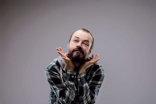 Stylish man with beard in studio, deep in thought, hands on face, curious expression, trendy portrait with copy space