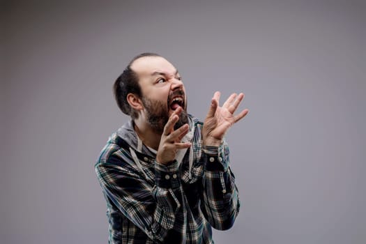 Bearded man screams angrily, gesturing wildly with hands, showing signs of aggression and stress in a portrait of intense upset and fury