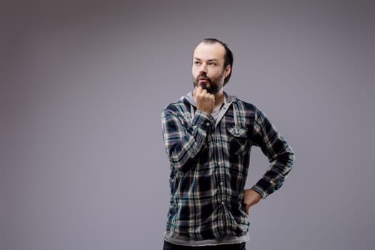 Young man with a beard is deep in thought, contemplating a decision or pondering a complex issue, conveying a sense of deep contemplation and engagement